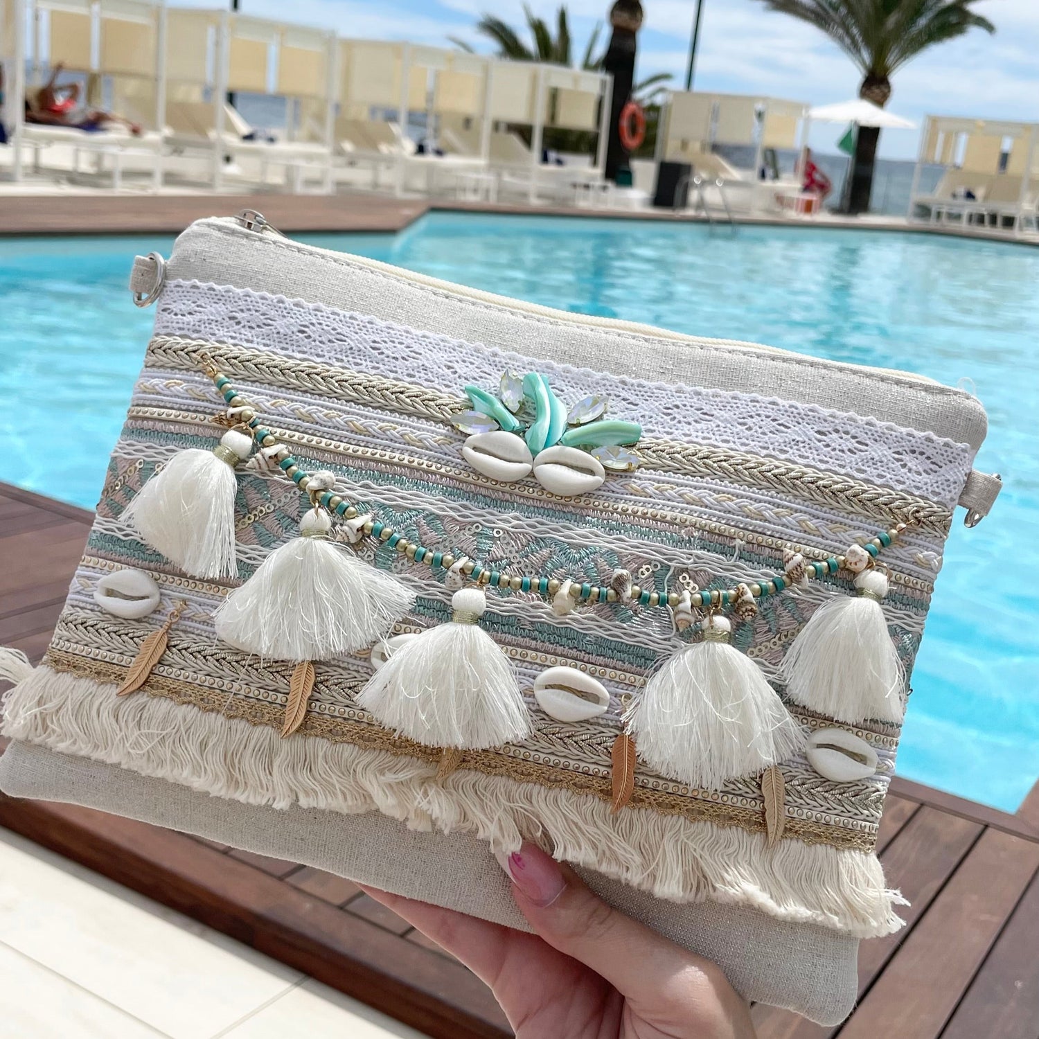Pochette d’été bleu bohème chic en tissu décorée de dentelle ajourée, tresse ethnique, pompons, perles bleues, plumes et coquillages – accessoire mode été femme Collection Ibiza avec bandoulière réglable